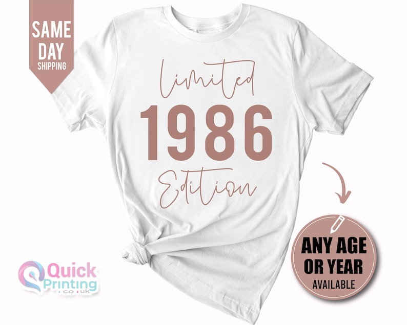 May include: A white short-sleeved t-shirt featuring the text Limited Edition in a cursive script font with the year 1986 printed in large, bold, dusty rose-colored block lettering centered on the front of the garment.