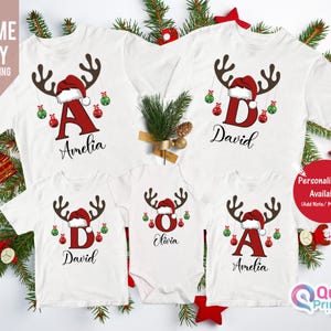 May include: White Christmas family t-shirts with reindeer antlers, Santa hats, and personalized names. Each shirt features a letter and name, with red and green ornaments. The image also includes the text "Personalisation Available".