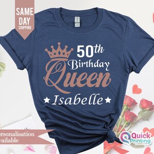 May include: A navy blue t-shirt with a gold crown and the text "50th Birthday Queen Isabelle" printed on it.