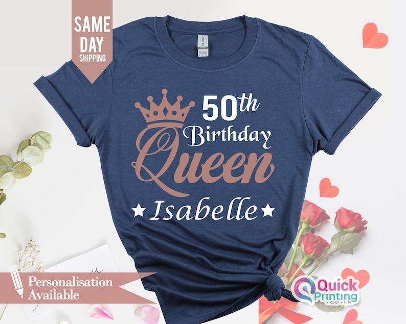 May include: A navy blue t-shirt with a gold crown and the text "50th Birthday Queen Isabelle" printed on it.
