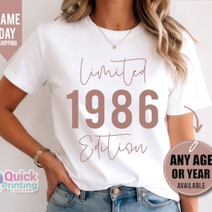 May include: A white short-sleeved t-shirt featuring the text Limited 1986 Edition in a brown script and block font. The shirt has a crew neckline and is worn with blue denim jeans. A circular graphic on the side states Any Age Or Year Available.
