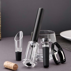 May include: A set of four wine accessories including a black and clear wine opener, a black and clear bottle stopper, a black and silver foil cutter, and a clear wine pourer.