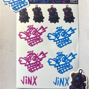 May include: A sheet of stickers featuring a cartoon character named Jinx. The stickers are in pink, blue, and black. The stickers feature the character's face, a robot, and the text "Jinx".