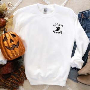 May include: White sweatshirt with a black ghost graphic and the text "Let's get spooky".