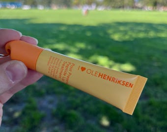May include: A yellow tube of lip treatment with the brand name "OLEHENRIKSEN" and the product name "Pout Present Peptide Lip Treatment" printed on the tube.