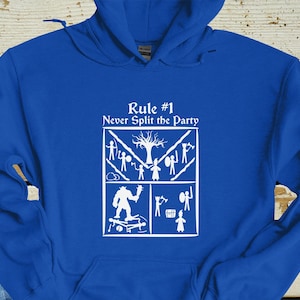 Könnte beinhalten: Ein königsblauer Hoodie mit einer weißen Grafik, auf der "Regel Nr. 1 Trenne dich niemals von der Gruppe" steht. Die Grafik zeigt eine Strichmännchen-Illustration einer Gruppe von Abenteurern.
