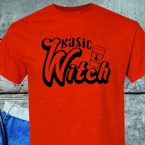 May include: Red t-shirt with black text that reads "basic witch" and a black and white illustration of a coffee cup with a witch flying inside.