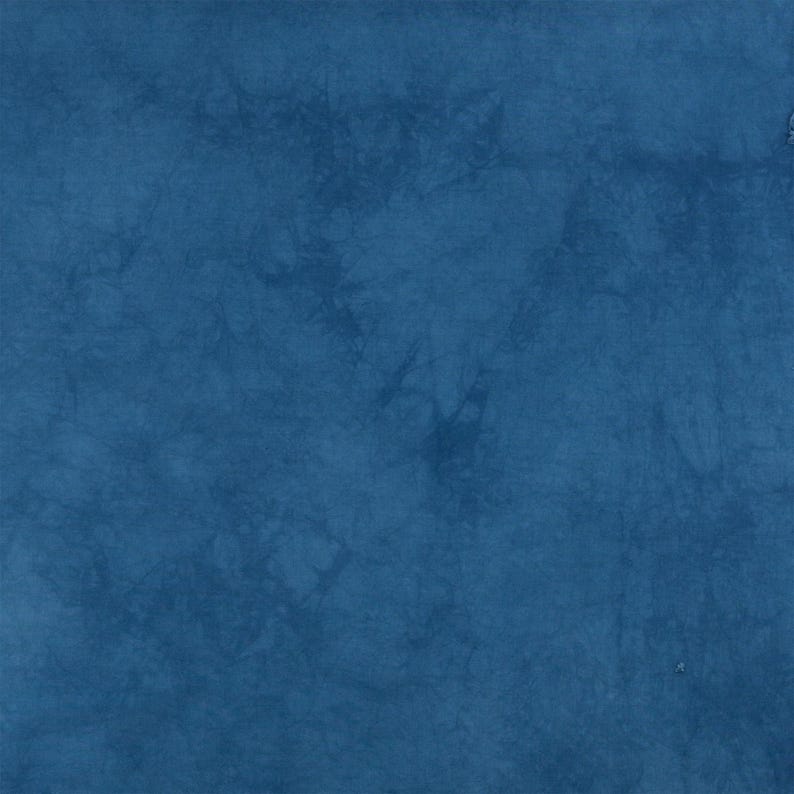K&ouml;nnte beinhalten: Ein tiefblauer Stoff mit einem gesprenkelten Batikmuster in verschiedenen Indigo- und Marine-T&ouml;nen. Die Oberfl&auml;che weist ein strukturiertes, organisches Erscheinungsbild auf, das durch den F&auml;rbeprozess entsteht und einen komplexen Effekt erzeugt.