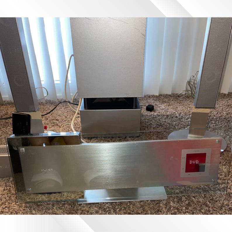 May include: A silver Sony DVD home theater system with a brushed metal finish. The system includes a main unit with a glass front, a subwoofer, and four speakers. The DVD player is visible on the front panel.
