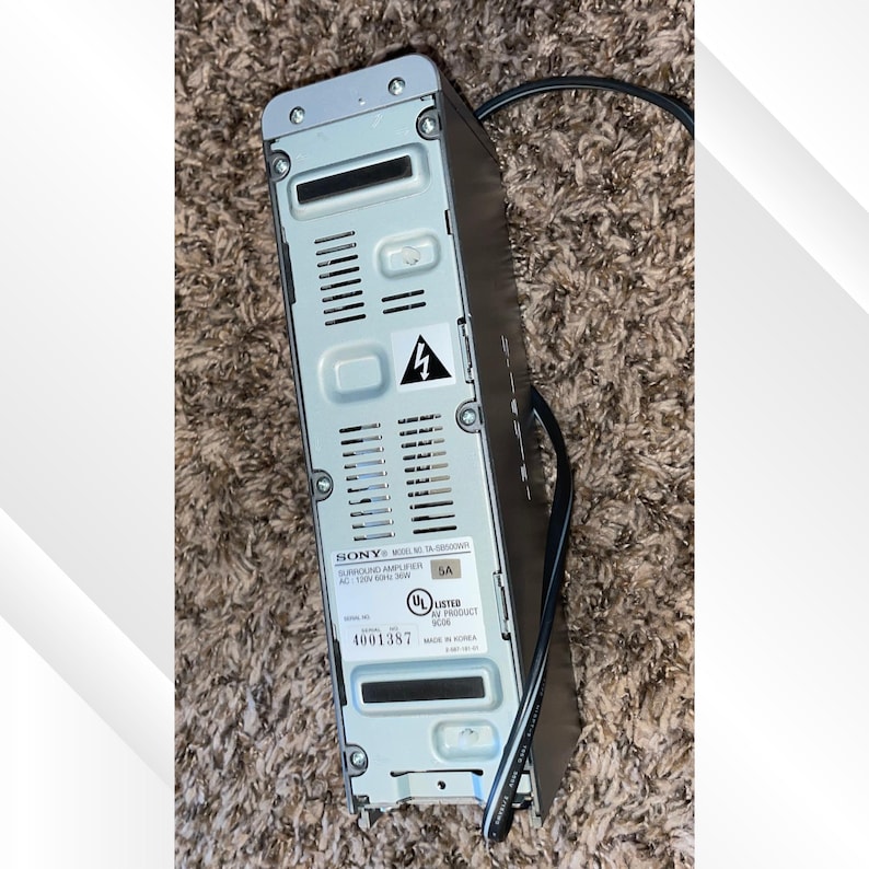 May include: A black Sony surround sound amplifier with a silver top. The back of the amplifier has ventilation slots, a warning symbol, and the model number. A black power cord is attached.
