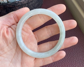 May include: A white jade bangle bracelet. The bracelet is smooth and polished.