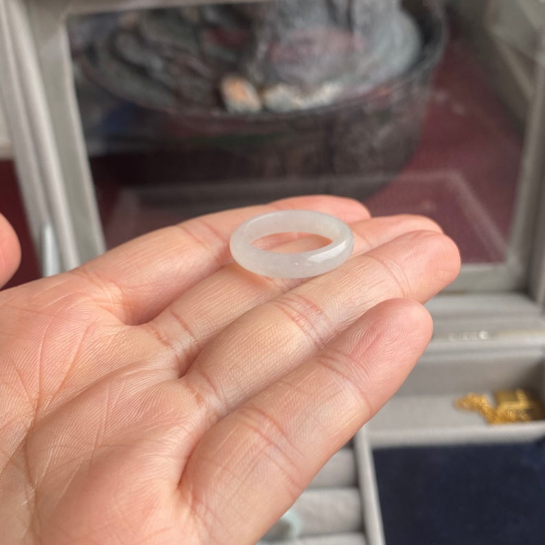 May include: A white jade ring with a smooth, polished finish. The ring is simple and elegant, and would make a beautiful addition to any jewelry collection.