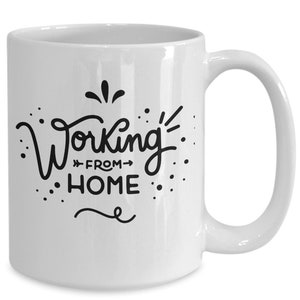 Könnte beinhalten: Weiße Keramik-Kaffeetasse mit einem schwarzen Design, auf dem in einer stilisierten Schrift "Working from home" steht.