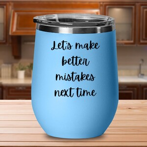 Puede incluir: Un vaso de vino de acero inoxidable azul claro con una inscripción negra que dice "Let's make better mistakes next time".