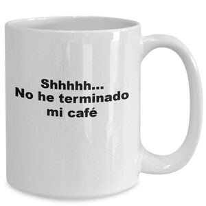 May include: White ceramic coffee mug with black text that reads "Shhhhh... No he terminado mi café".
