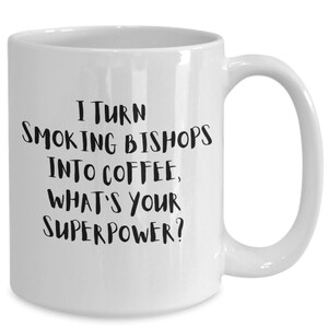 Könnte beinhalten: Weiße Keramik-Kaffeetasse mit schwarzem Text, der lautet: "Ich verwandele rauchende Bischöfe in Kaffee, was ist deine Superkraft?"