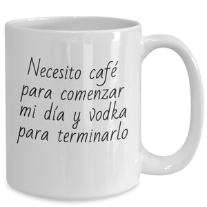 May include: White ceramic coffee mug with black text that reads "Necesito café para comenzar mi día y vodka para terminarlo".
