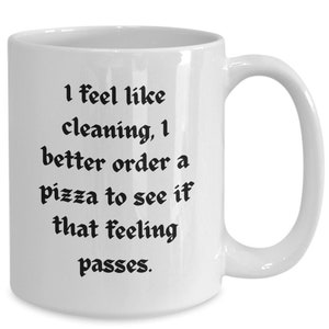 Puede incluir: Taza de café de cerámica blanca con texto negro que dice "Tengo ganas de limpiar, mejor pido una pizza para ver si se me pasa este sentimiento."