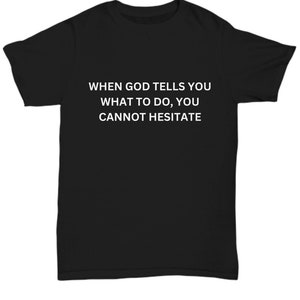 Peut inclure: T-shirt noir avec un texte blanc qui dit "WHEN GOD TELLS YOU WHAT TO DO, YOU CANNOT HESITATE."