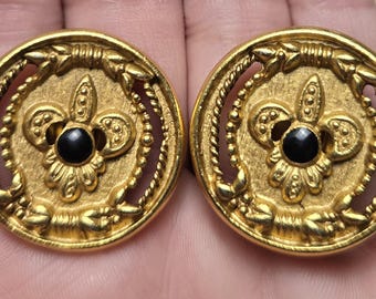 Pendientes redondos de clip vintage en tono dorado con centros de flor de lis, esmalte negro y diseño calado.