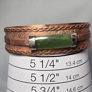 Puede incluir: Pulsera de cobre con incrustaciones de piedra verde y detalles plateados. La pulsera mide 13,4 cm de circunferencia.