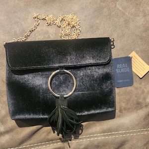 May include: Black velvet crossbody bag with a gold chain strap, a gold ring accent, and a black tassel. The bag has a tag that reads "Real Suede" and "Street Level".