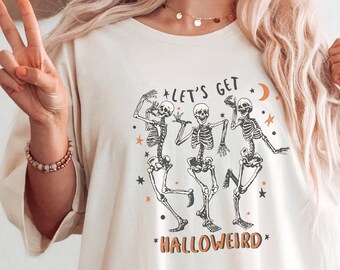 May include: A white t-shirt featuring a graphic of three skeletons dancing. The text "Let's Get Hallowweird" is printed on the shirt.
