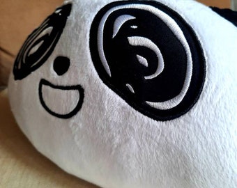 May include: White plush panda pillow with black embroidered eyes and a smiling mouth.