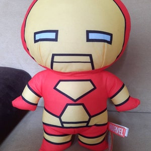 May include: A red and yellow plush toy of Iron Man from Marvel. The toy has a large head with a black eye mask and a red and yellow body with a black outline.
