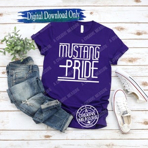 Puede incluir: Camiseta morada con texto blanco que dice "Mustang Pride". La camiseta está sobre una superficie de madera con un par de vaqueros y zapatillas blancas.