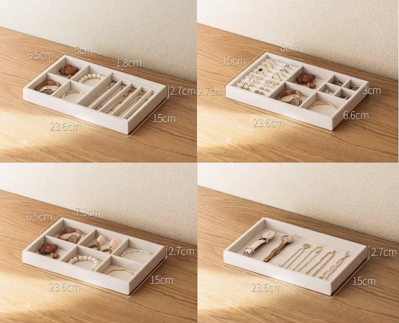 May include: A rectangular beige jewelry organizer tray with multiple compartments for storing accessories. The tray measures 23.6 cm in length, 15 cm in width, and 2.7 cm in height. It features various internal dividers to hold watches, bracelets, rings, and necklaces.