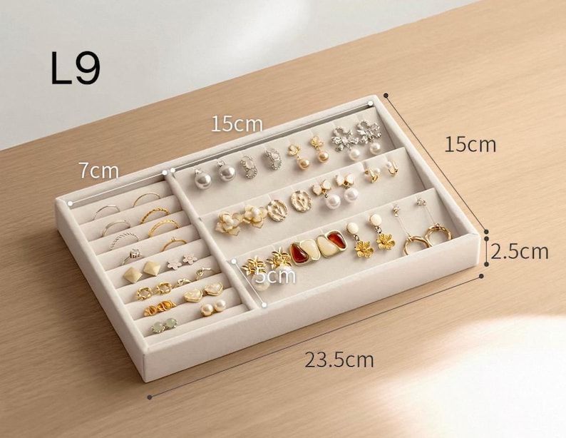 May include: A beige velvet jewelry organizer tray labeled L9, measuring 23.5 cm by 15 cm by 2.5 cm. The tray features a left section for rings and a right section for earrings, with a 7 cm and 5 cm internal divider width visible.