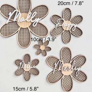 K&ouml;nnte beinhalten: Vier h&ouml;lzerne, blumenf&ouml;rmige Wanddekorationen mit verschiedenen Namen darauf. Die Namen sind Molly, Poppy, Millie und Marley. Die Blumen haben einen Durchmesser von 30 cm, 20 cm, 15 cm und 25 cm.
