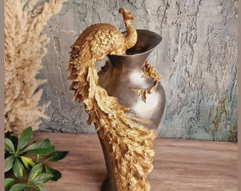 Puede incluir: Un jarrón de cerámica con forma de pavo real con las plumas de la cola extendidas, pintado en dorado. El jarrón está sobre una superficie de madera.