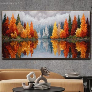 May include: An oil painting shows a forest with autumn foliage reflected in a lake. The artwork features trees in shades of orange, yellow, and green, with a cloudy sky above. The painting is displayed in a gold frame.