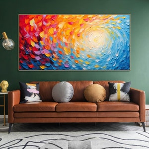 May include: Abstract painting with a swirling pattern of red, orange, yellow, blue, and purple hues. The painting is framed and hanging on a green wall above a brown leather sofa.