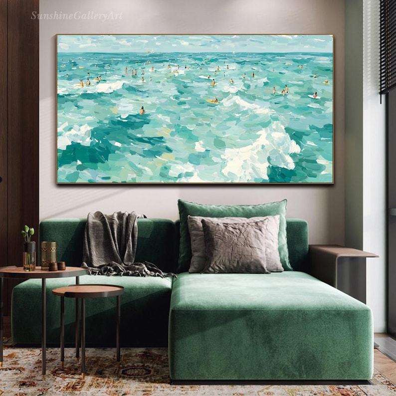 May include: An abstract painting of a turquoise ocean with numerous figures surfing. The artwork features a palette of blues and greens, with white brushstrokes depicting waves. The painting is framed and hangs above a green sofa.