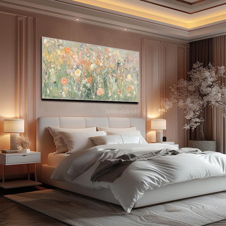 Op de afbeelding: Een groot rechthoekig schilderij met een bloemenontwerp hangt boven een bed. Het kunstwerk toont een mix van oranje, gele en witte bloemen tegen een groene achtergrond. De kamer heeft een modern design met een wit bed, nachtkastjes en lampen.