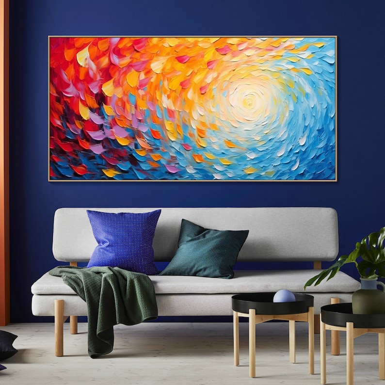 May include: Abstract painting with a swirling pattern of red, orange, yellow, blue, and purple. The painting is framed in gold and hangs on a blue wall.