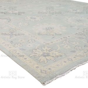 May include: A light blue rug with a white and light blue floral pattern. The rug has a fringed edge.