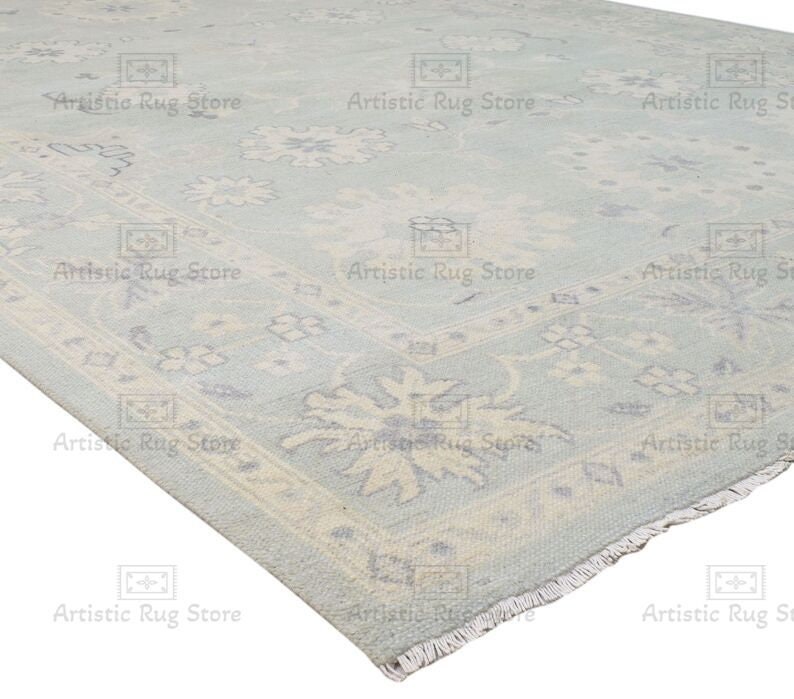 May include: A light blue rug with a white and light blue floral pattern. The rug has a fringed edge.