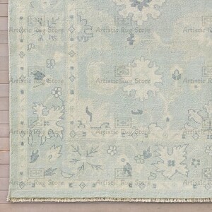May include: A light blue rug with a faded, distressed pattern. The rug has a fringe border and a subtle, vintage look.