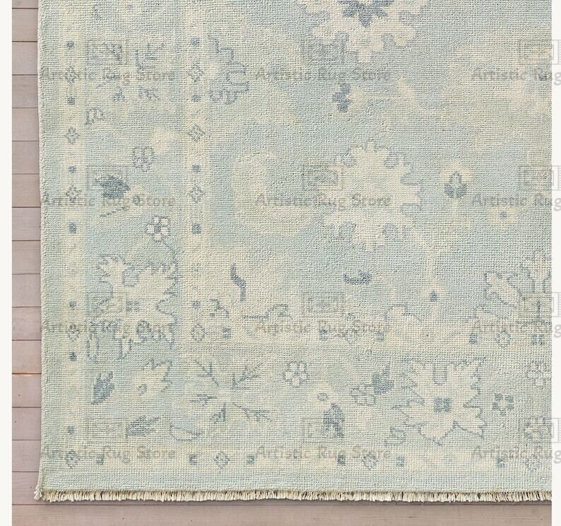 May include: A light blue rug with a faded, distressed pattern. The rug has a fringe border and a subtle, vintage look.