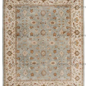 Puede incluir: Una alfombra azul claro con un borde beige. La alfombra tiene un patrón floral con un diseño repetitivo de pequeñas flores y hojas.