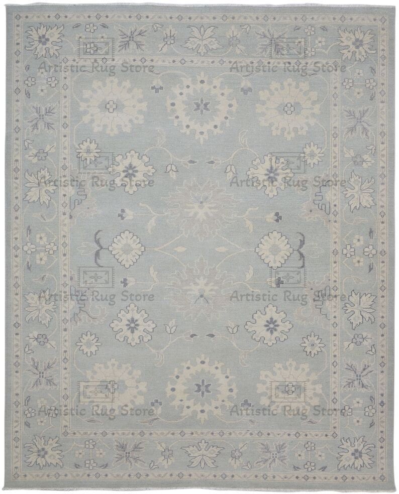 May include: A light blue rug with a traditional Persian design featuring white and gray floral patterns. The rug has a border with a repeating diamond pattern.