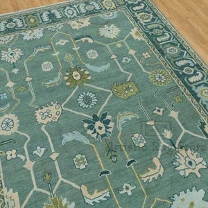 a green rug with a blue border on a wooden floor