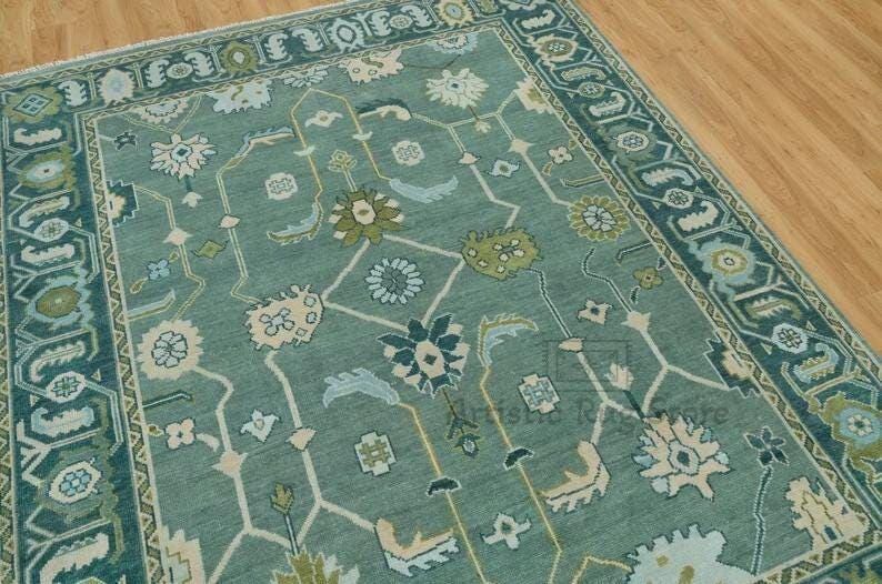 a green rug with a blue border on a wooden floor