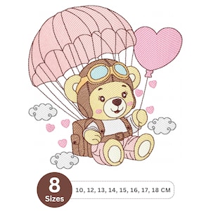 Pode incluir: Design bordado com um urso de pelúcia com chapéu e óculos de piloto, flutuando com um paraquedas e um balão em forma de coração. O design inclui nuvens e corações, com opções de tamanho de 10 a 18 cm.