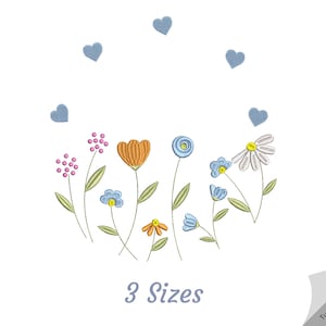 May include: An embroidered design of various flowers and green leaves, with blue hearts above. The design includes an orange tulip, daisies, and other floral elements. The text "3 Sizes" is below the floral design.
