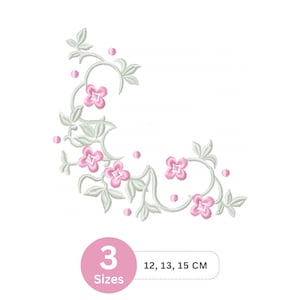 May include: An embroidered floral design with pink flowers, pale green leaves, and small pink dots, arranged in a corner. The image includes text indicating three size options: 12, 13, and 15 cm. A decorative floral motif.